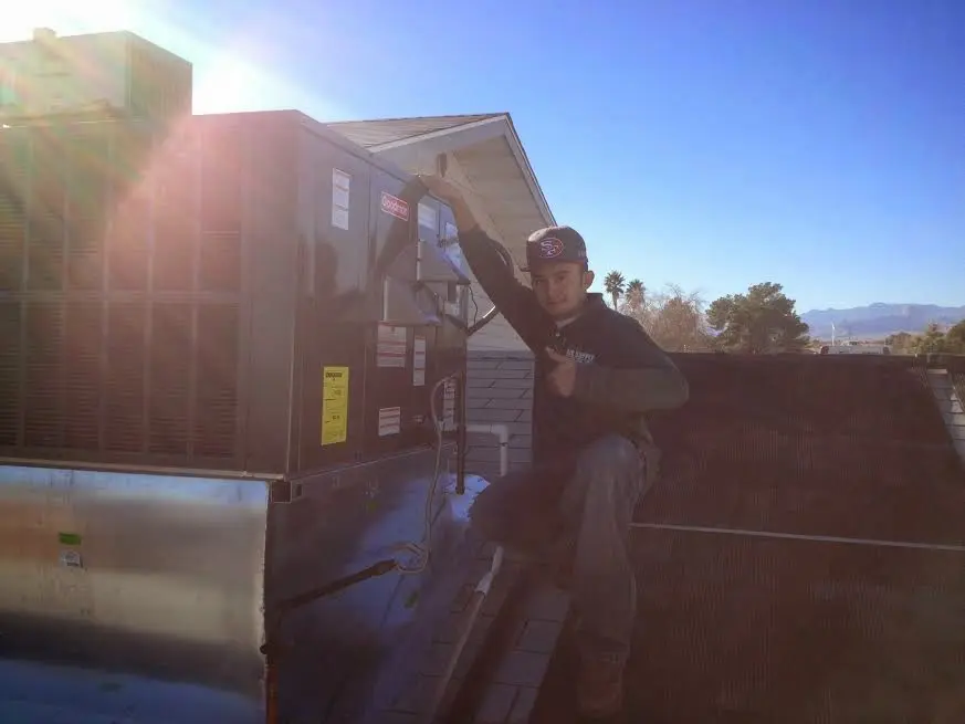 HVAC technician performing Air Duct Repair on a rooftop unit in Laketown